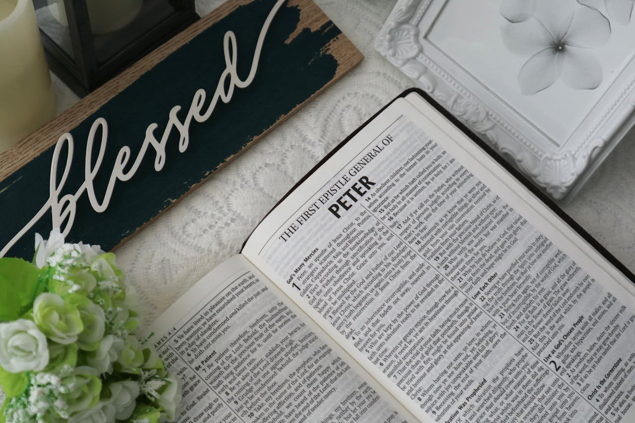 Top view of an open Bible with a 'blessed' sign and floral decor, conveying a serene and spiritual atmosphere.
