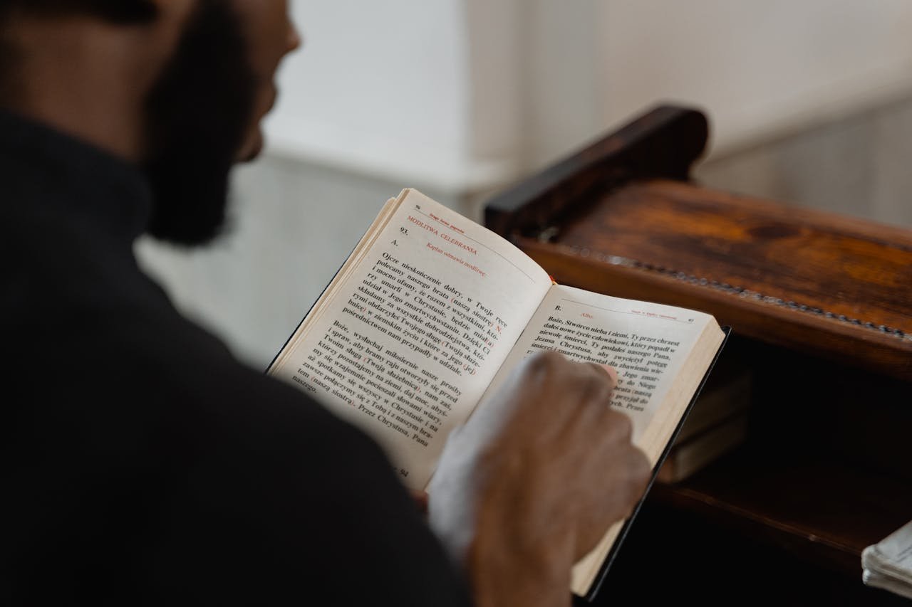 A man reading a religious book inside a church, focusing on a spiritual moment.